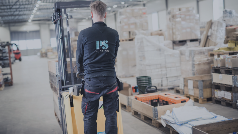 Truckförare hanterar utrustning i lager inför försäljning via företagsauktion